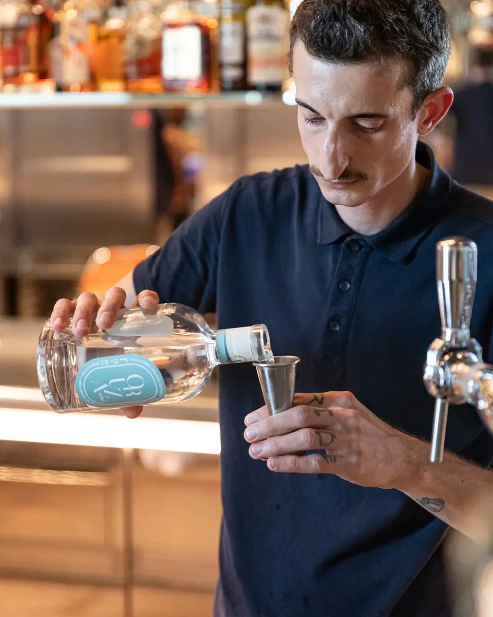 Barman tenant une bouteille pour fabriquer un cocktail.
