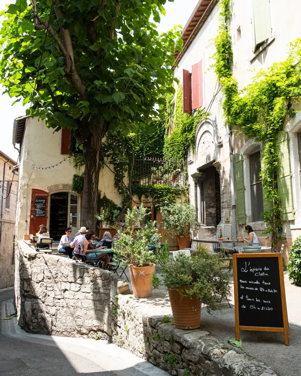 Valet de chambre qui arrange des rideaux dans un salon de l'hôtel L'Arlatan à Arles.